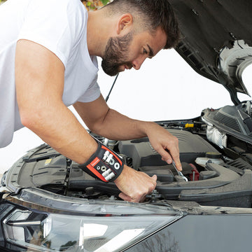 Magnetisches Heimwerkerarmband am Handgelenk hält Werkzeuge beim Arbeiten am Auto.
