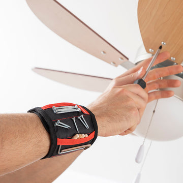 Magnetisches Armband hält Schrauben und Nägel. Heimwerker befestigt Deckenventilator mit Schraubendreher.