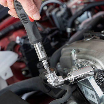 Universal Steckschlüssel mit Zubehör im Einsatz am Auto. Das Werkzeug ist silberfarben.
